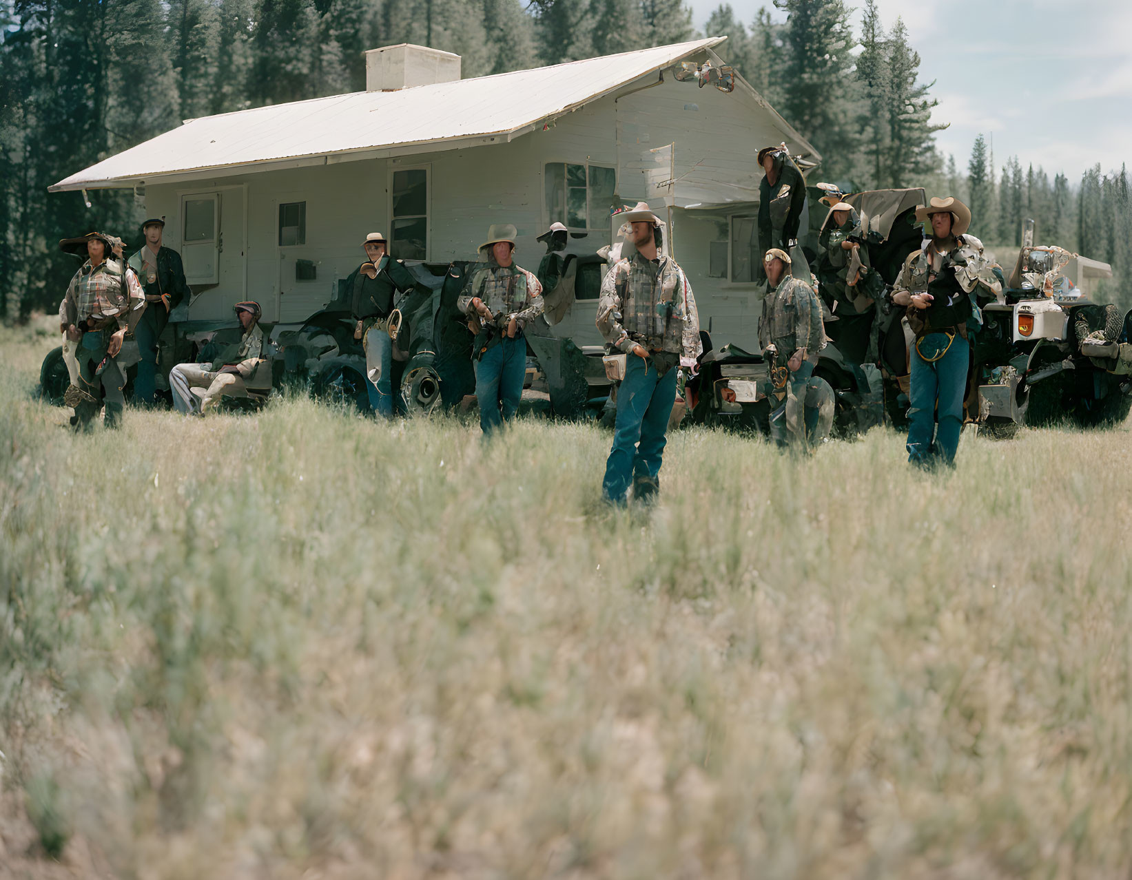 Cowboy-themed group with vintage trailer and ATVs in grassy field