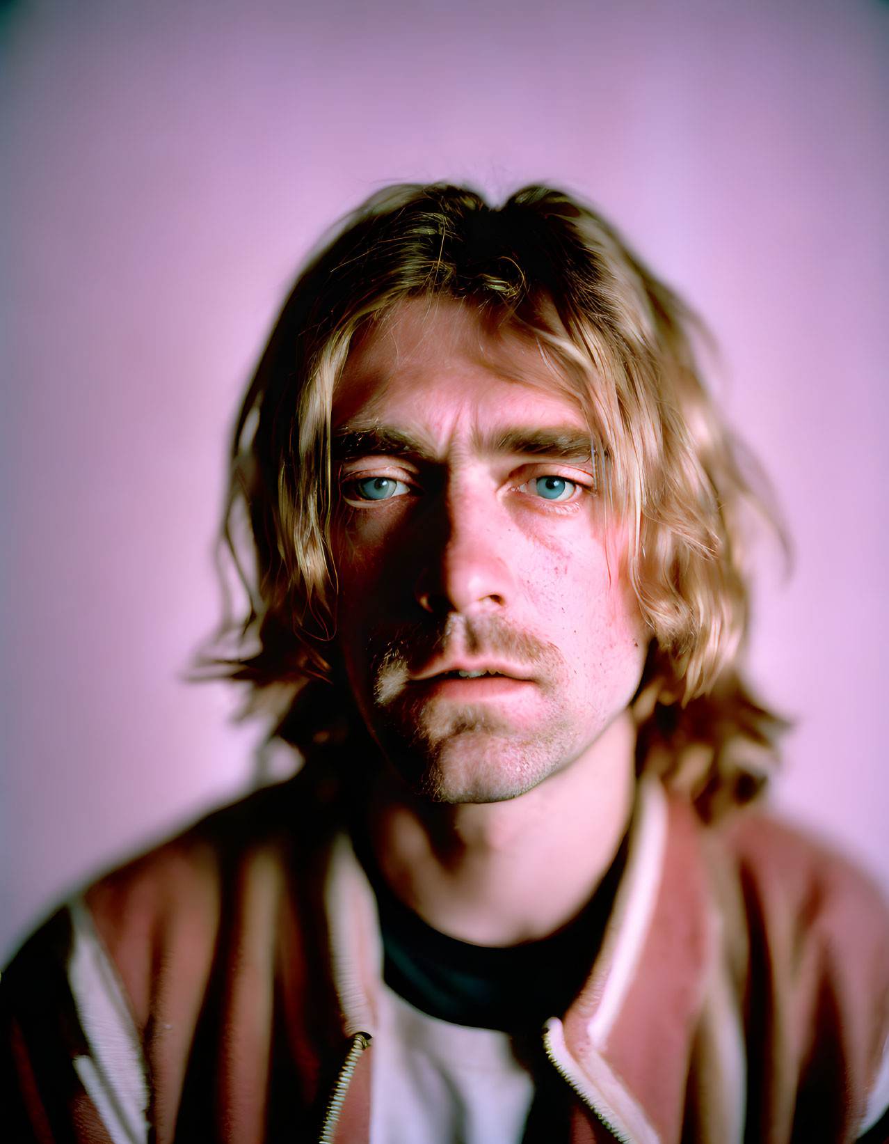 Man with Medium-Length Wavy Blond Hair and Stubble on Pink Background