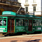 Vintage Green Tram with Passengers on City Street Amid Elegant Buildings