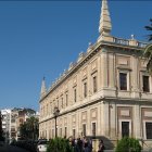 Historic European Building with Steeple and Palm Trees Under Dramatic Sky