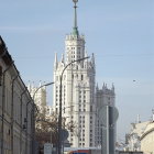 Vintage-style snowy scene with old-fashioned cars, ornate building, and street lamps.