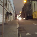 Twilight cobblestone street with lit lamp posts and quaint houses