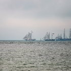 Sailboat illustration near village with lighthouse on wavy seas