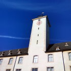 Traditional European Building with Tower in Pale Pink Against Deep Blue Sky