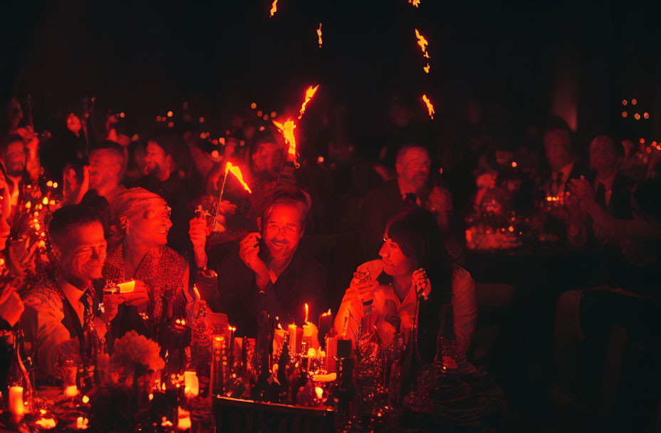 Group of people enjoying candlelit event with warm, festive glow and sparklers.