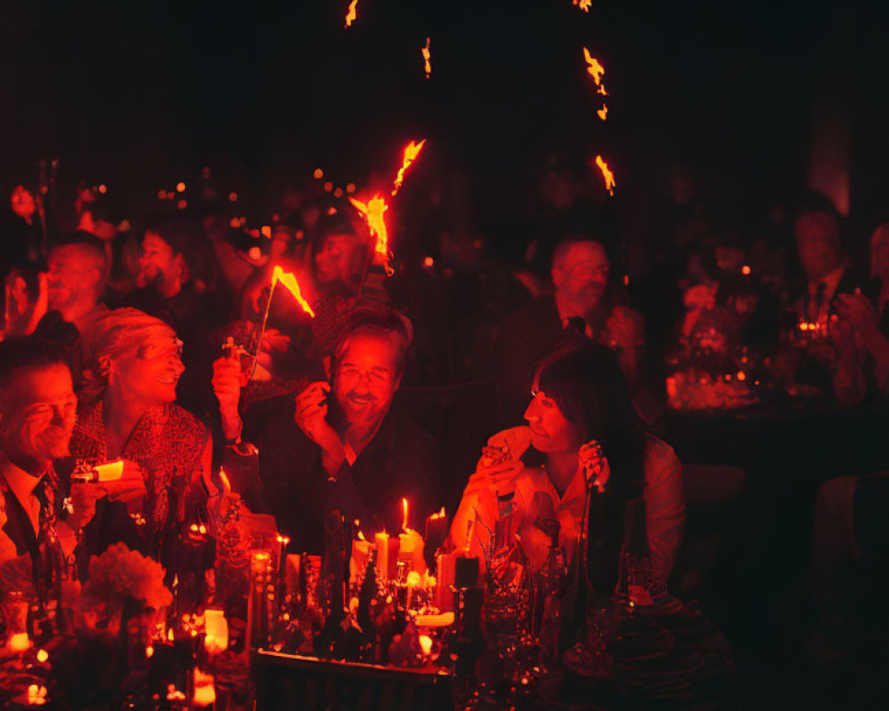 Group of people enjoying candlelit event with warm, festive glow and sparklers.