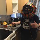 Two men in kitchen with tattoos and fake beard pointing at each other