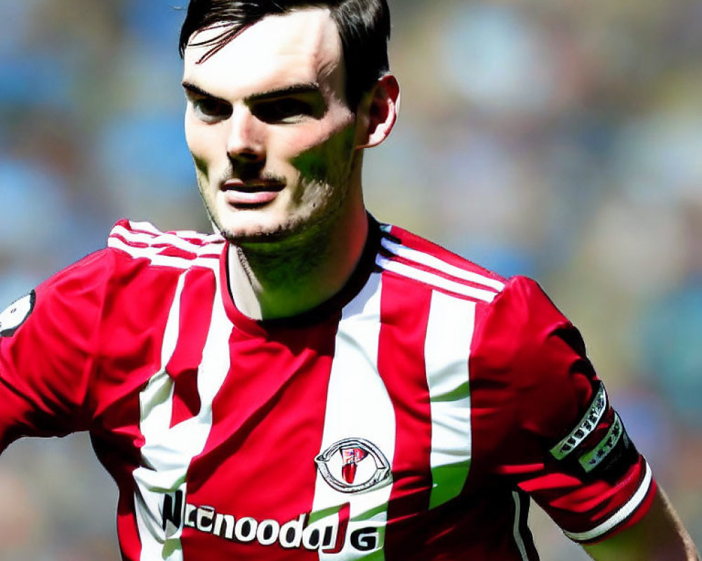 Short-haired person in red and white soccer jersey at stadium.