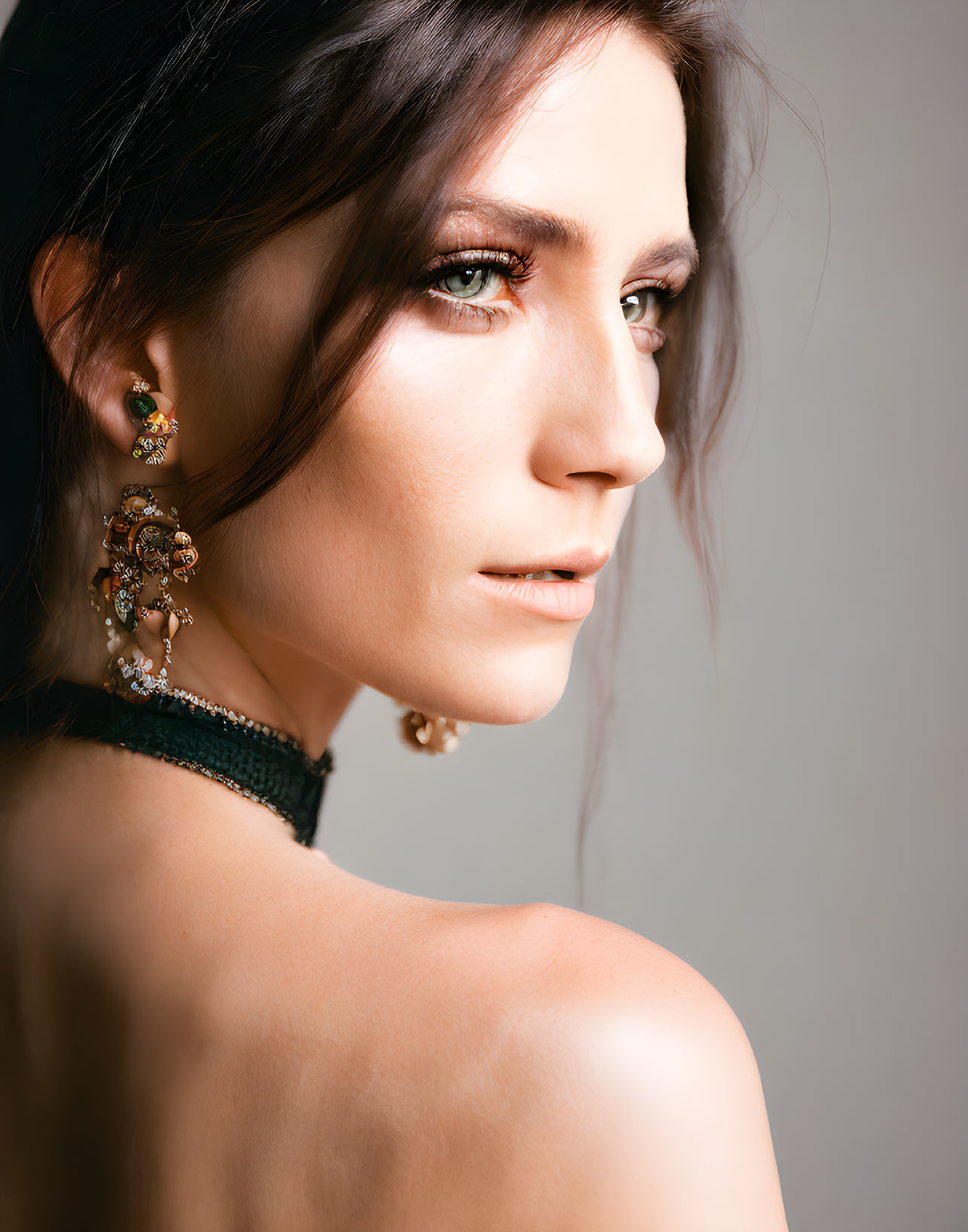 Profile of woman with smoky eye makeup and ornate earrings in velvet choker.