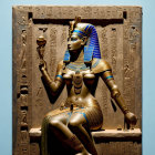 Ancient Egyptian-style artwork with seated figure and hieroglyphs