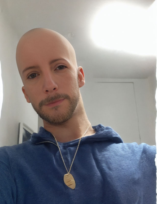 Bald Person in Blue Hoodie Smiling for Selfie