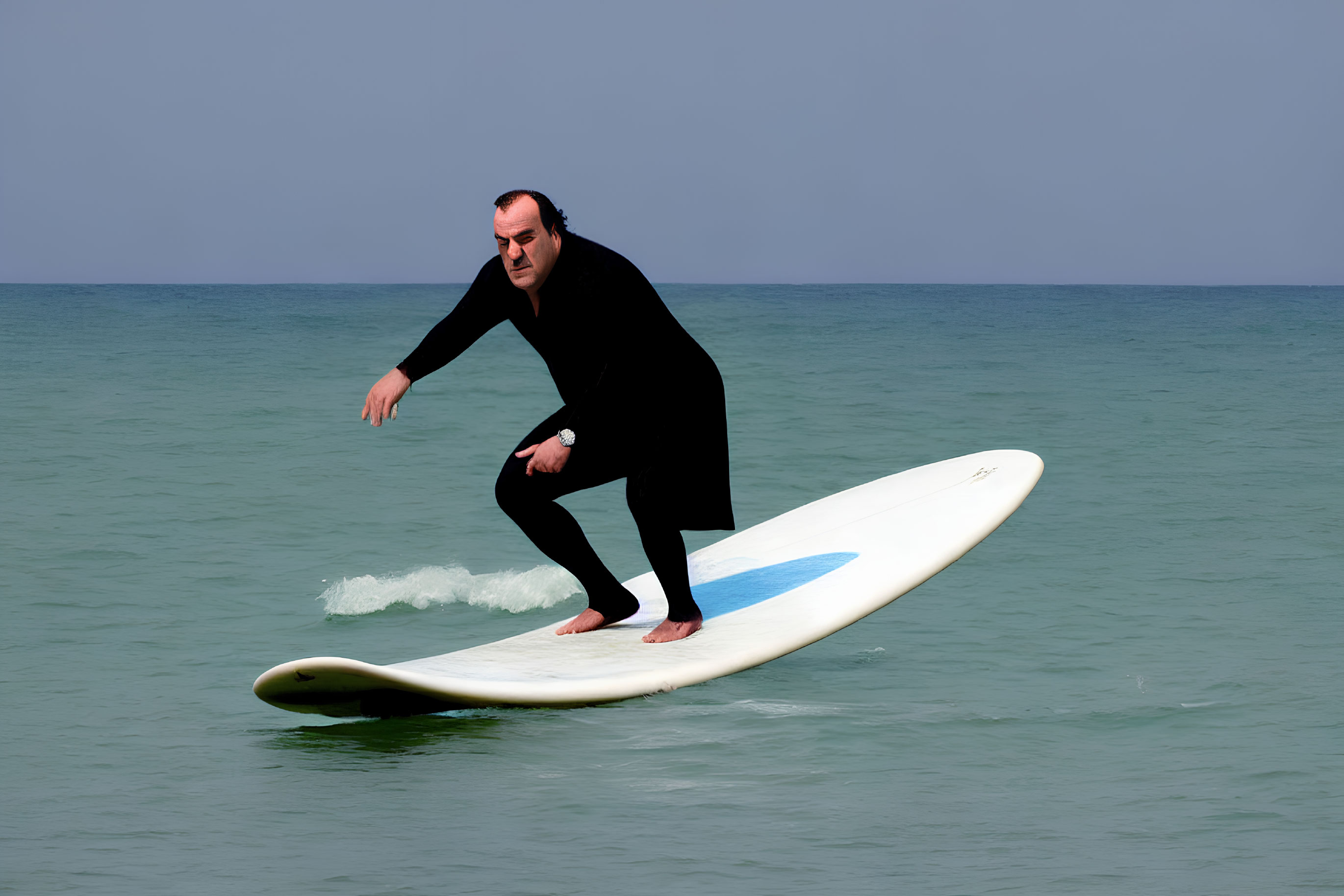 Surfer in black wetsuit on calm ocean under clear blue sky