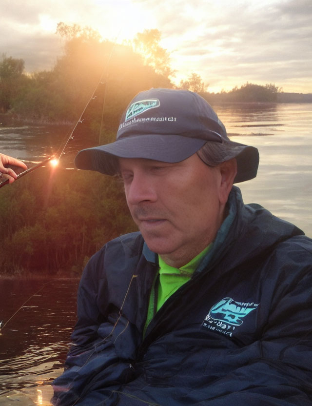 Man in hat and jacket fishing on boat at dawn or dusk with trees and sunlight on water