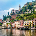 Vibrant lakeside village scene with lush hills and mountain backdrop