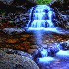 Tranquil waterfall scene with colorful leaves and lush greenery