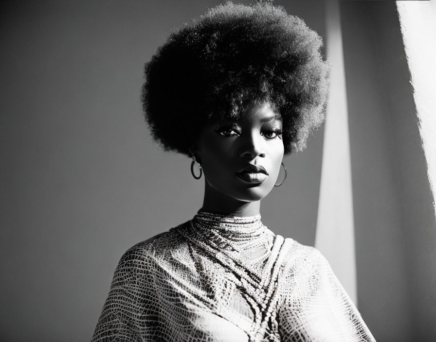 Monochrome image of woman with afro and hoop earrings in textured top