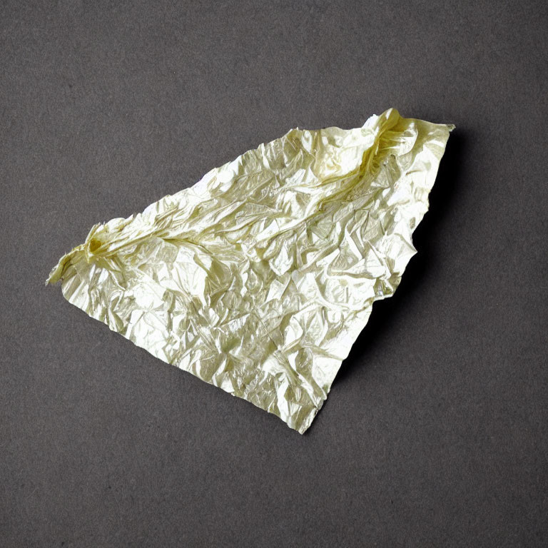 Yellowish Crumpled Aluminum Foil on Dark Gray Background