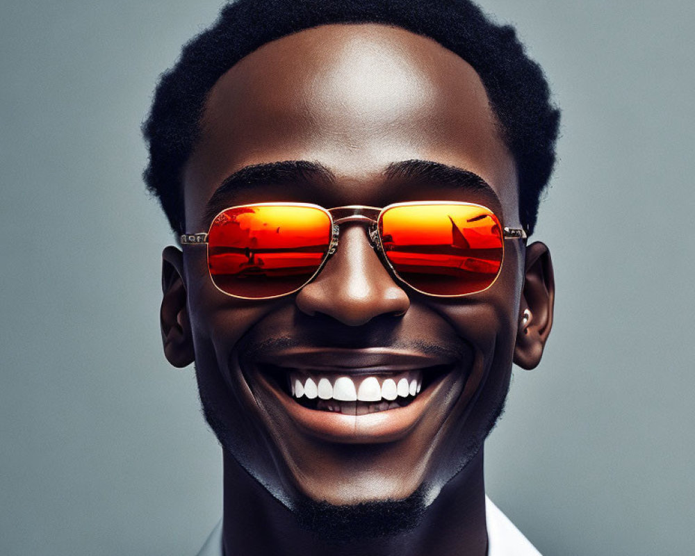 Smiling man in orange sunglasses on grey background