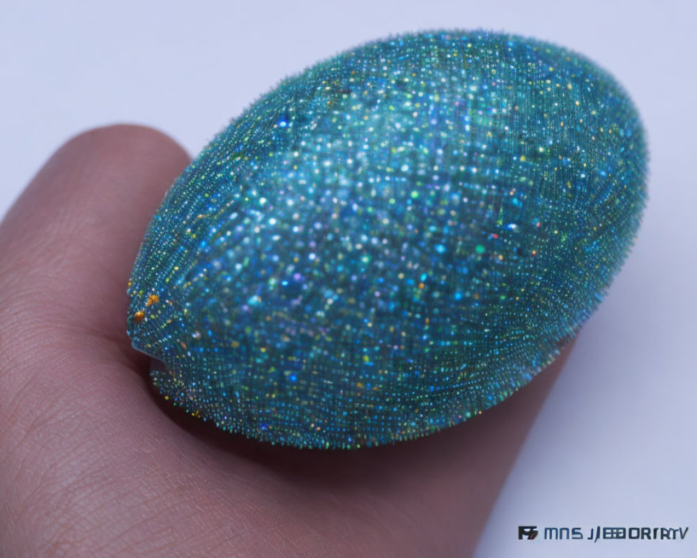 Shiny Turquoise and Blue Speckled Egg on Human Finger