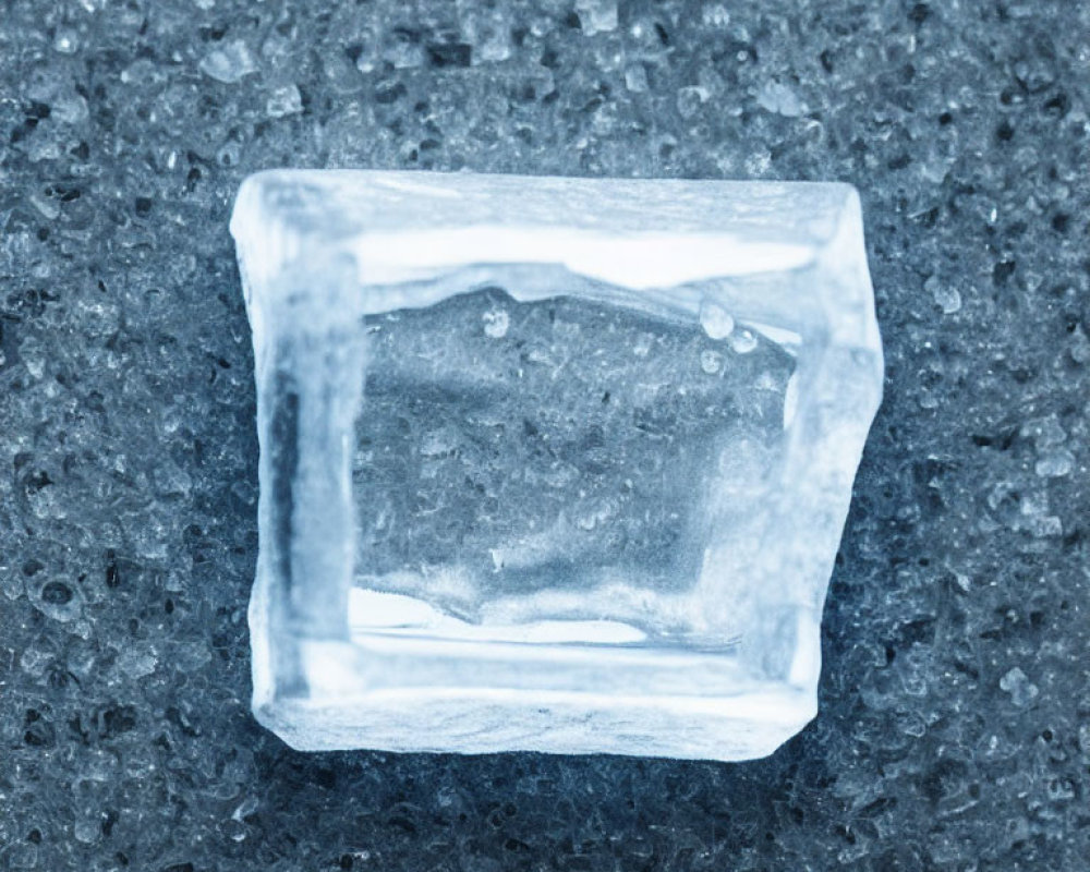 Translucent ice cube with air bubbles on rough surface