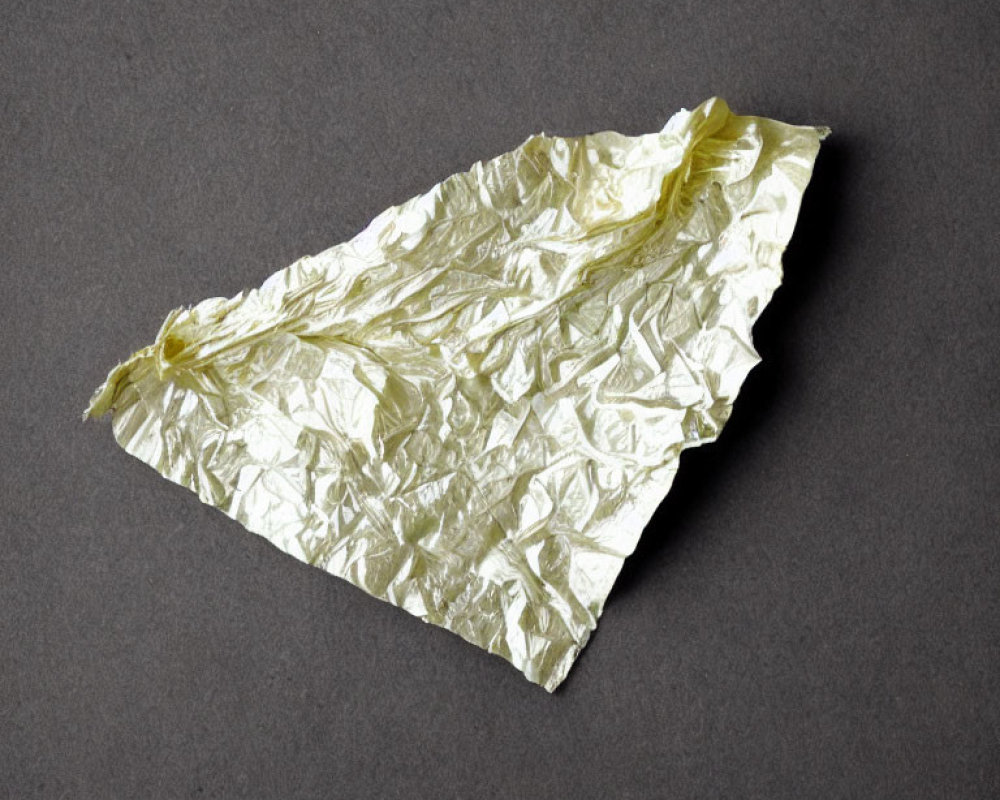 Yellowish Crumpled Aluminum Foil on Dark Gray Background