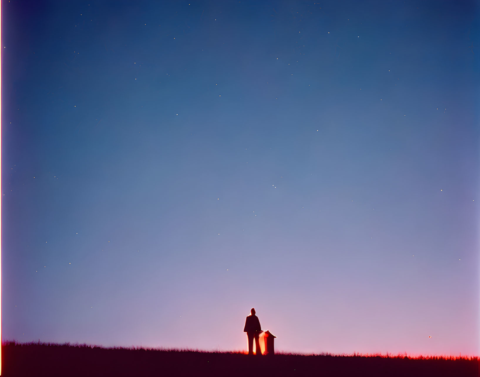 Solitary figure under starry twilight sky on hill