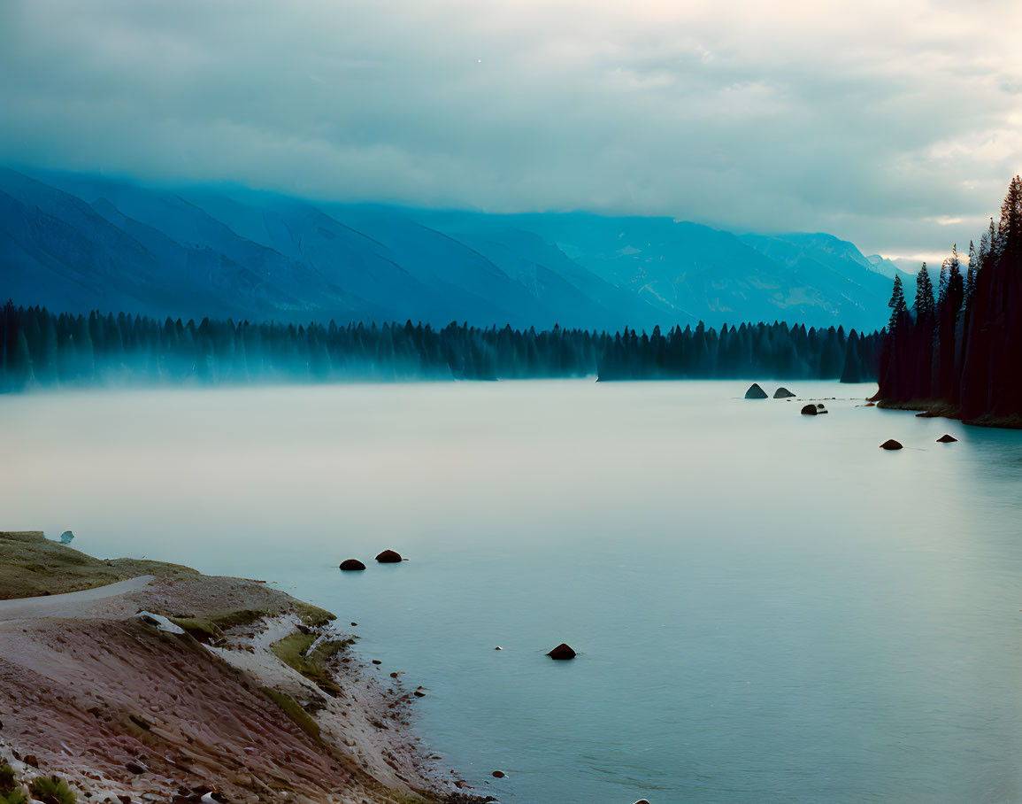 Misty lake in forested mountains under hazy sky