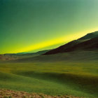 Grassy landscape at night with green aurora borealis.