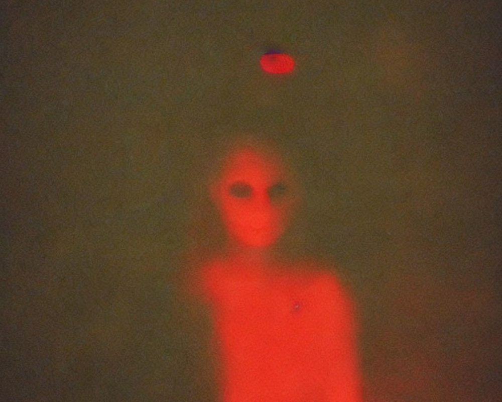 Blurred figure under red light in dim, grainy setting