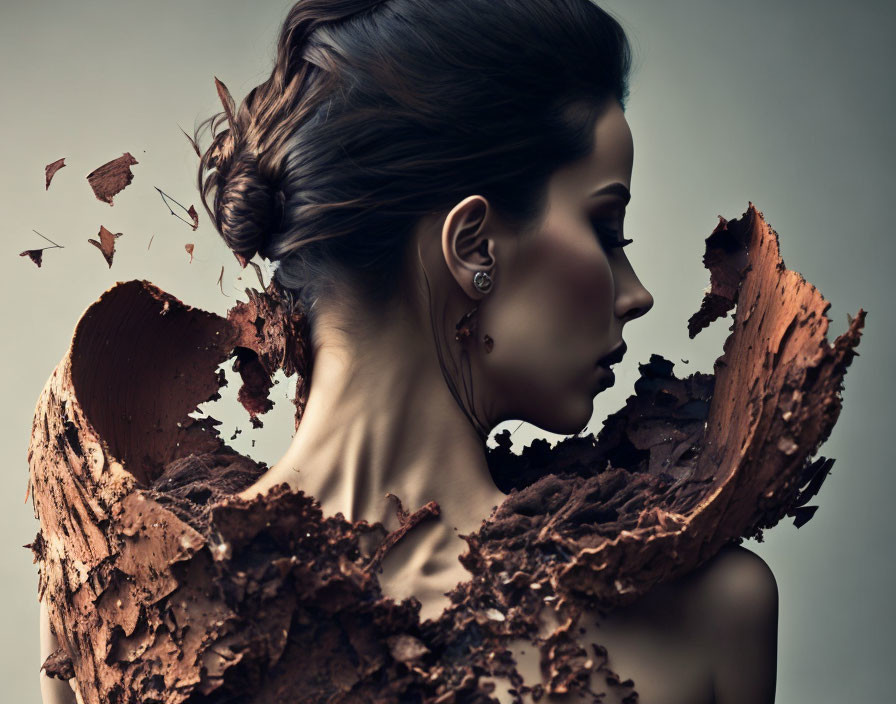 Profile view of woman with elegant updo and abstract, crumbling textures merging on her shoulder