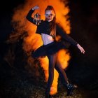 Vibrant dancer in black attire against flowing orange and blue backdrop