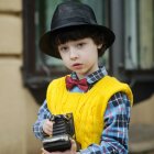 Illustration of young boy with turntable head, hat, yellow sweater, holding vinyl record