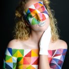 Portrait of a woman with contemplative expression in multicolored geometric mosaic.