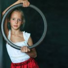 Young girl holding shattered mirror with floating pieces, wearing white blouse and red skirt