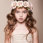 Young girl with floral crown and wavy brown hair in muted tones.