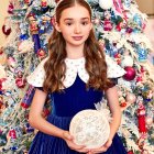 Holiday-themed illustration: Woman in blue and white dress with glowing orb by Christmas tree and squirrel