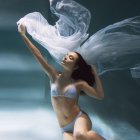 Woman in sparkly bikini underwater surrounded by swirling smoke and bubbles