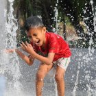Child in Red Shirt Splashing Water in Nature Background
