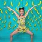 Young girl with flowing hair and yellow birds in turquoise setting wearing floral dress