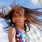 Child with flowing hair and sunglasses in surreal mountain scene