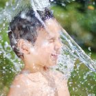 Child splashed with water in serene green setting