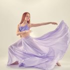 Woman in lilac dress by water with floating fish-like creatures