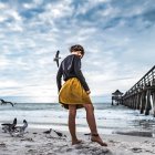 Young girl in yellow dress on stormy beach near shipwreck