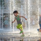 Children playing and skipping in rain with colorful fallen leaves and street lamps reflections