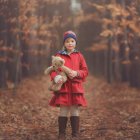 Child in Red Coat Surrounded by Vibrant Garden