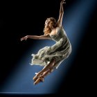 Colorful flowing dress dancer in mid-air against dark background