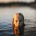 Woman's face split between sunset and stormy seascape in unique image