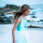 Ethereal woman with silver hair and blue dress by the sea