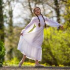 Young girl in floral dress with pinwheel in vibrant spring garden