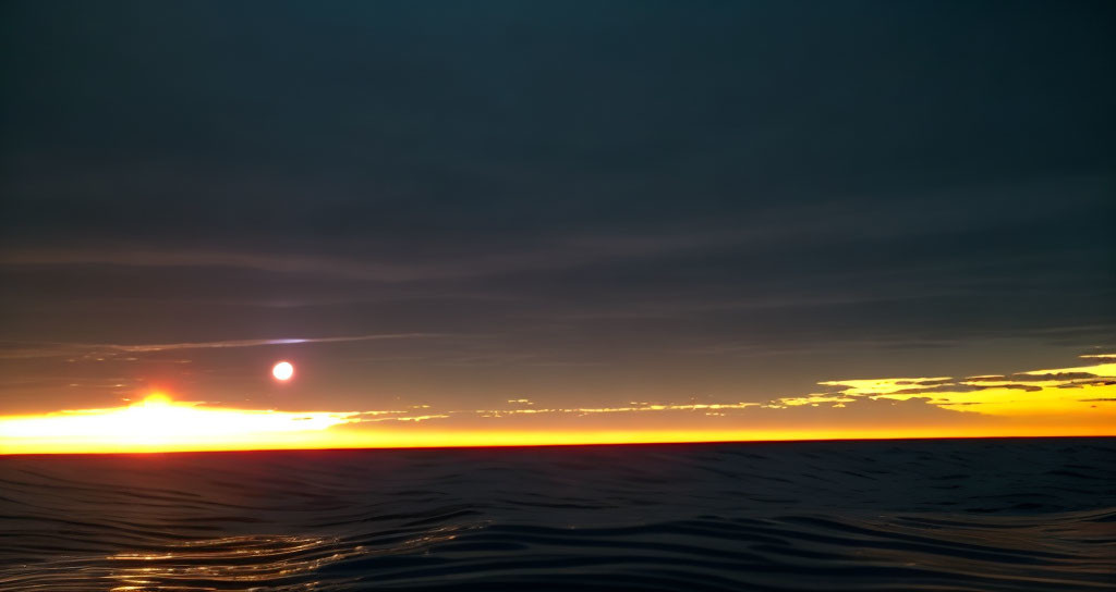 Tranquil sunset over serene sea with orange and blue sky.